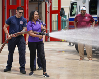 Save a Life with Commissioner Colbourne holding a Fire Hose